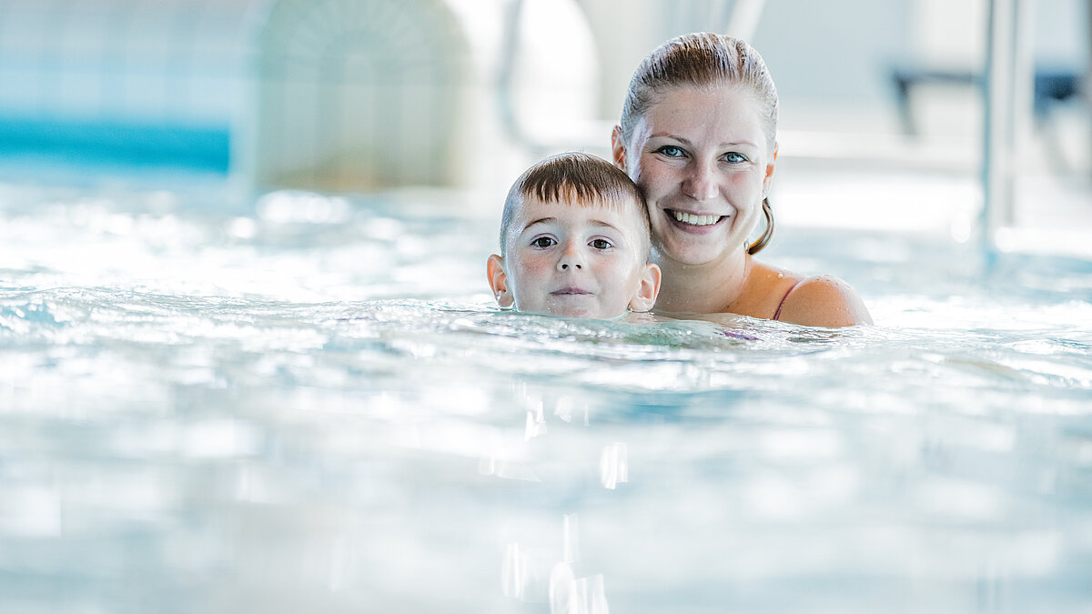 Grafik: Frau freut sich gemeinsam mit kleinem Jungen im Becken des Hallenbads. 