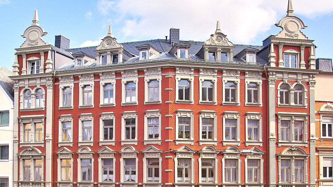 Grafik: Rotes Mehrfamilienhaus im Altbaustil.