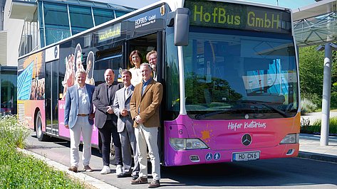 Foto zeigt bunt beklebten Stadtbus mit der Aufschrift "Hofer Kulturbus". In der Anzeigetafel ist "HofBus GmbH" zu lesen. Vor dem Bus posieren fünf Personen - vier Männer und eine Frau.